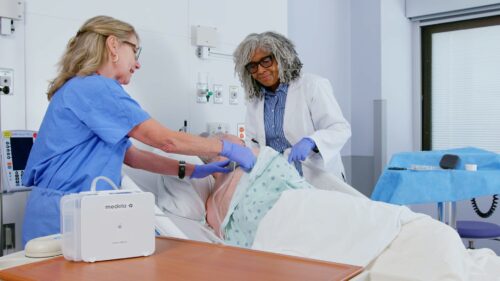 Two healthcare professionals dress a wound with a NPWT device